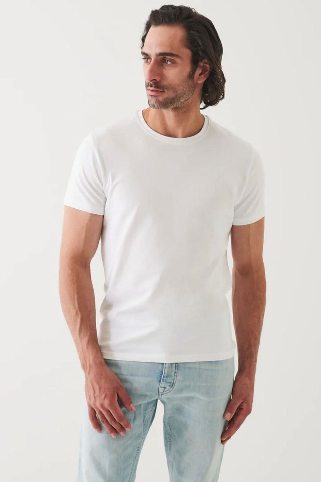 Homme portant un t-shirt basique blanc à la coupe moderne avec manches courtes et encolure ronde.