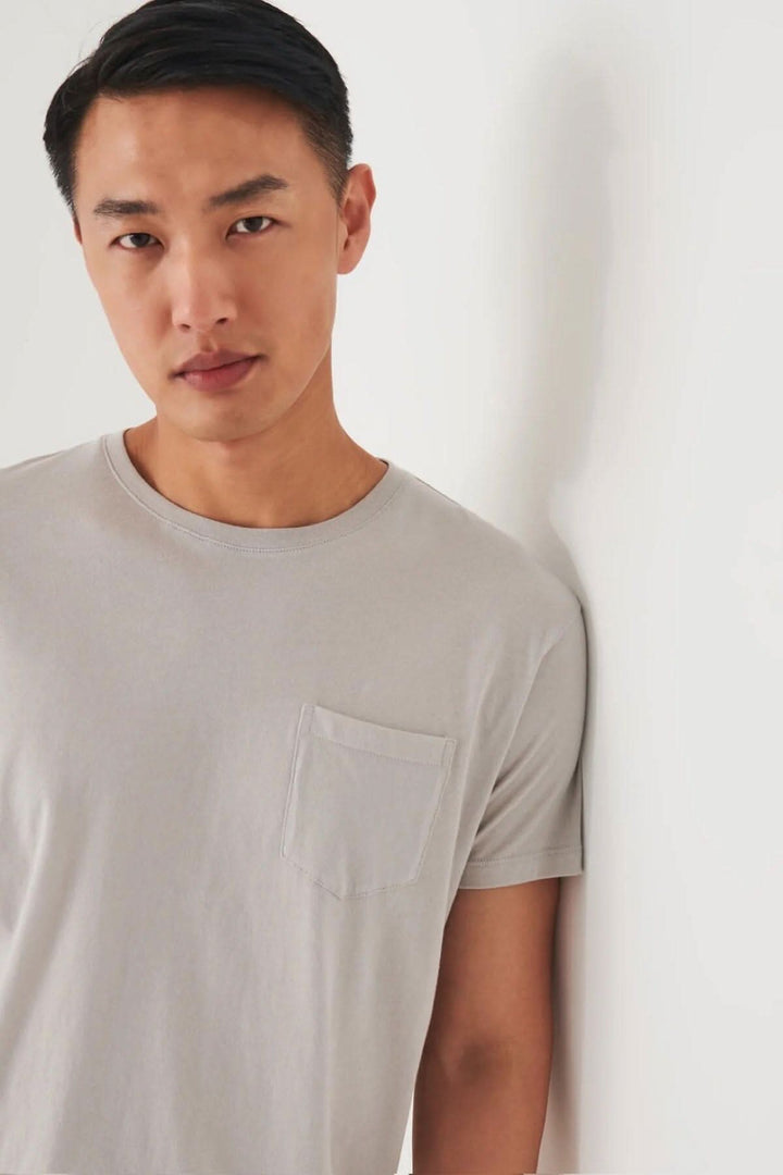 Man wearing a light gray pima cotton t-shirt with a pocket, styled for a casual look against a white background.