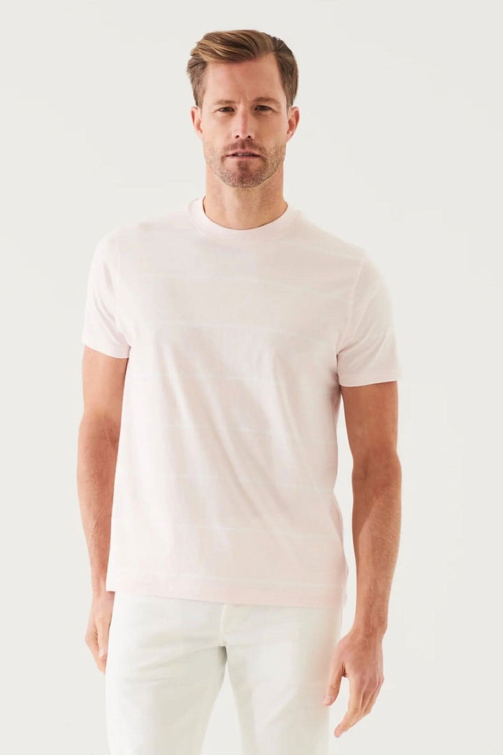 Homme portant un t-shirt rayé en coton pima mercerisé, coupe régulière, couleur rose, col ras du cou.