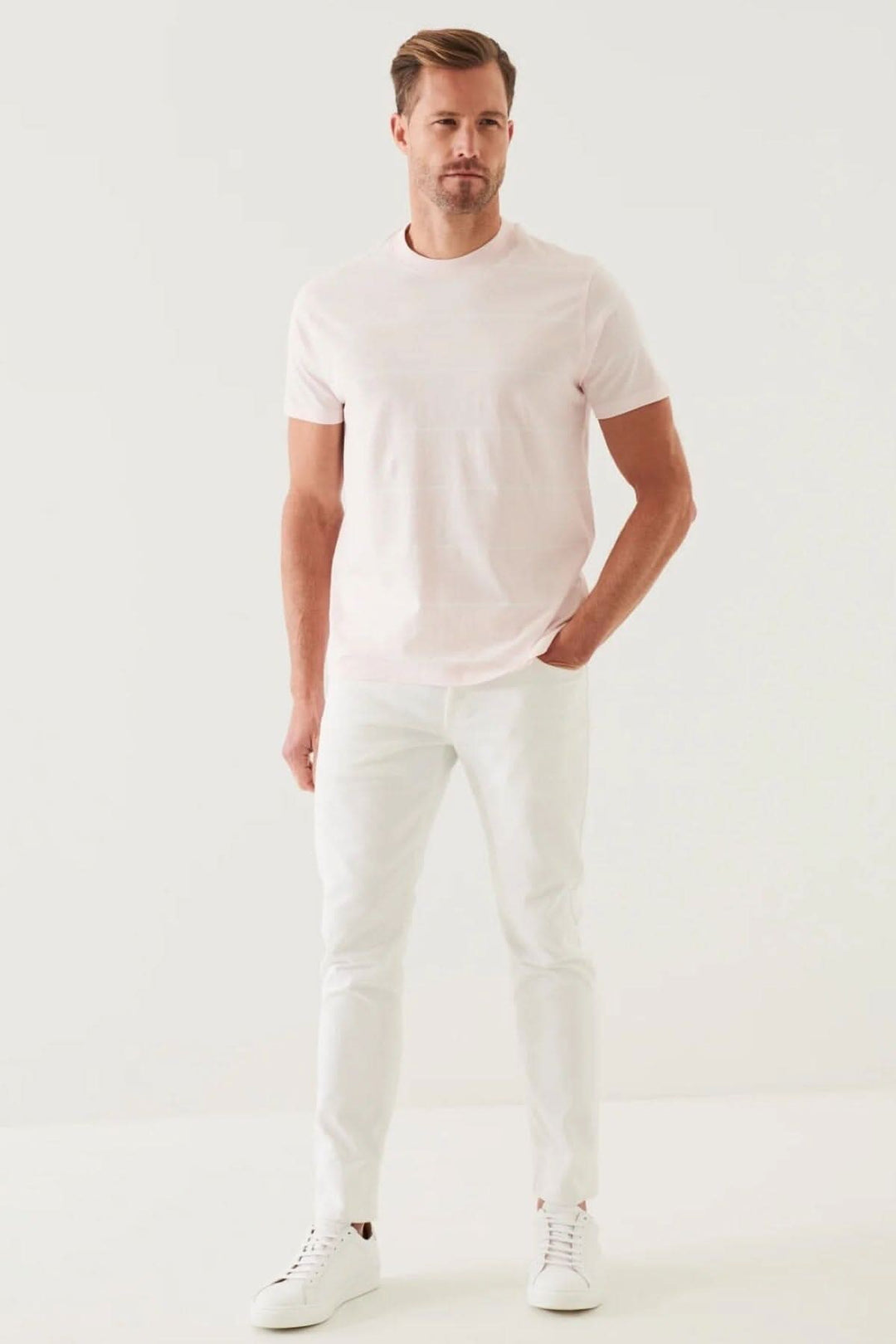 Homme portant un t-shirt rayé en coton pima rose et un pantalon blanc, style décontracté.