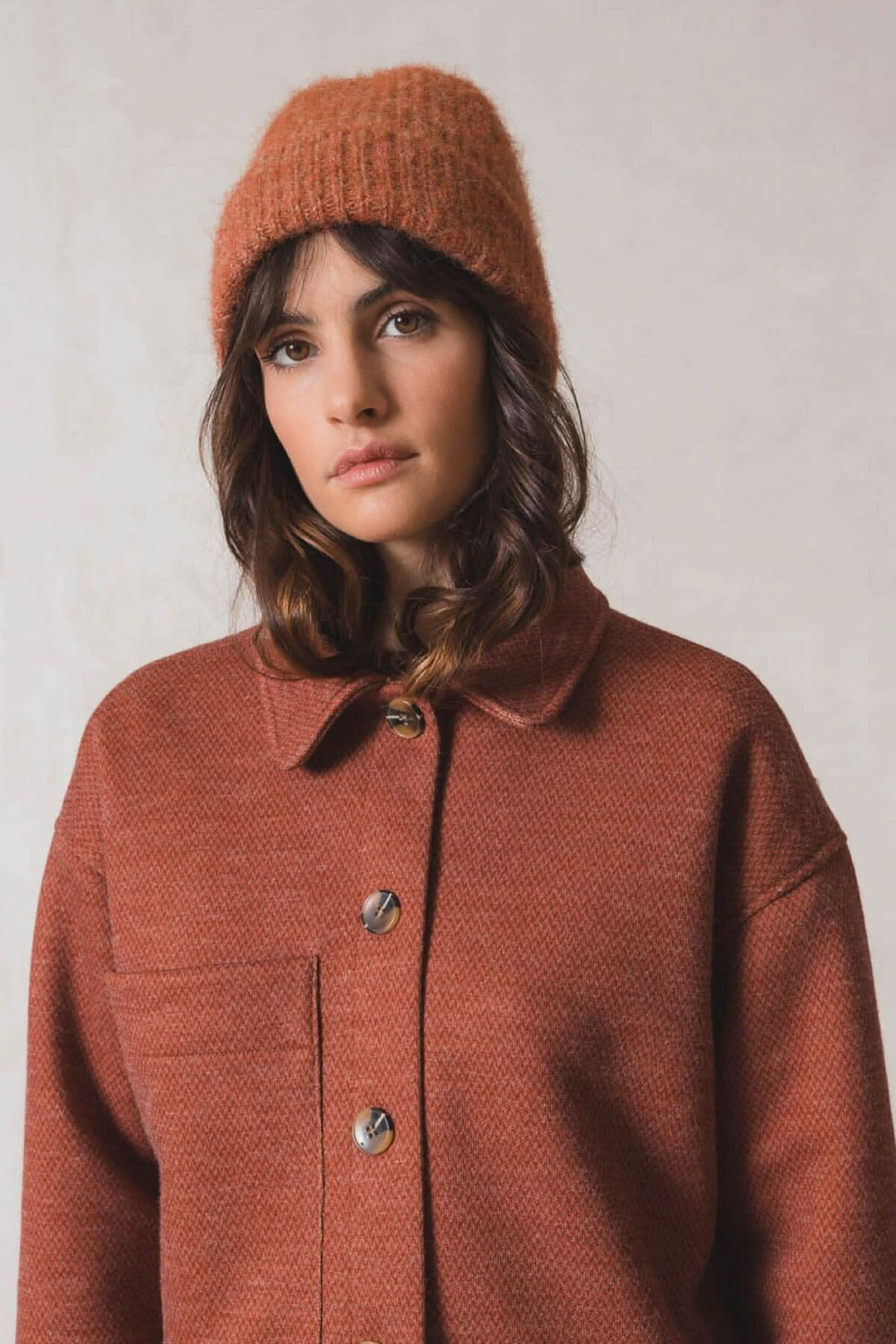 Femme portant une tuque en tricot orange et une veste assortie, style élégant et décontracté.