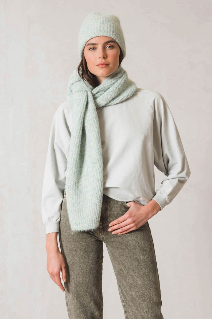 Femme portant une tuque en tricot et une écharpe, tenue confortable et stylée en tons de bleu clair.