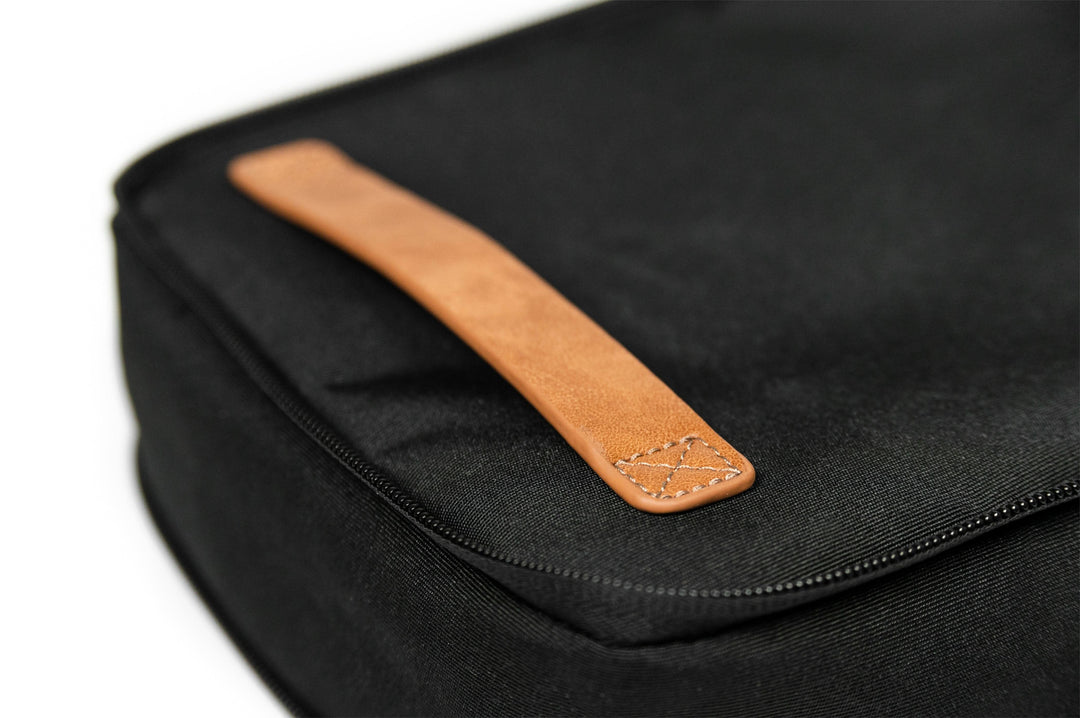 Close-up of a black packing cube featuring a sleek leather handle for easy carrying.