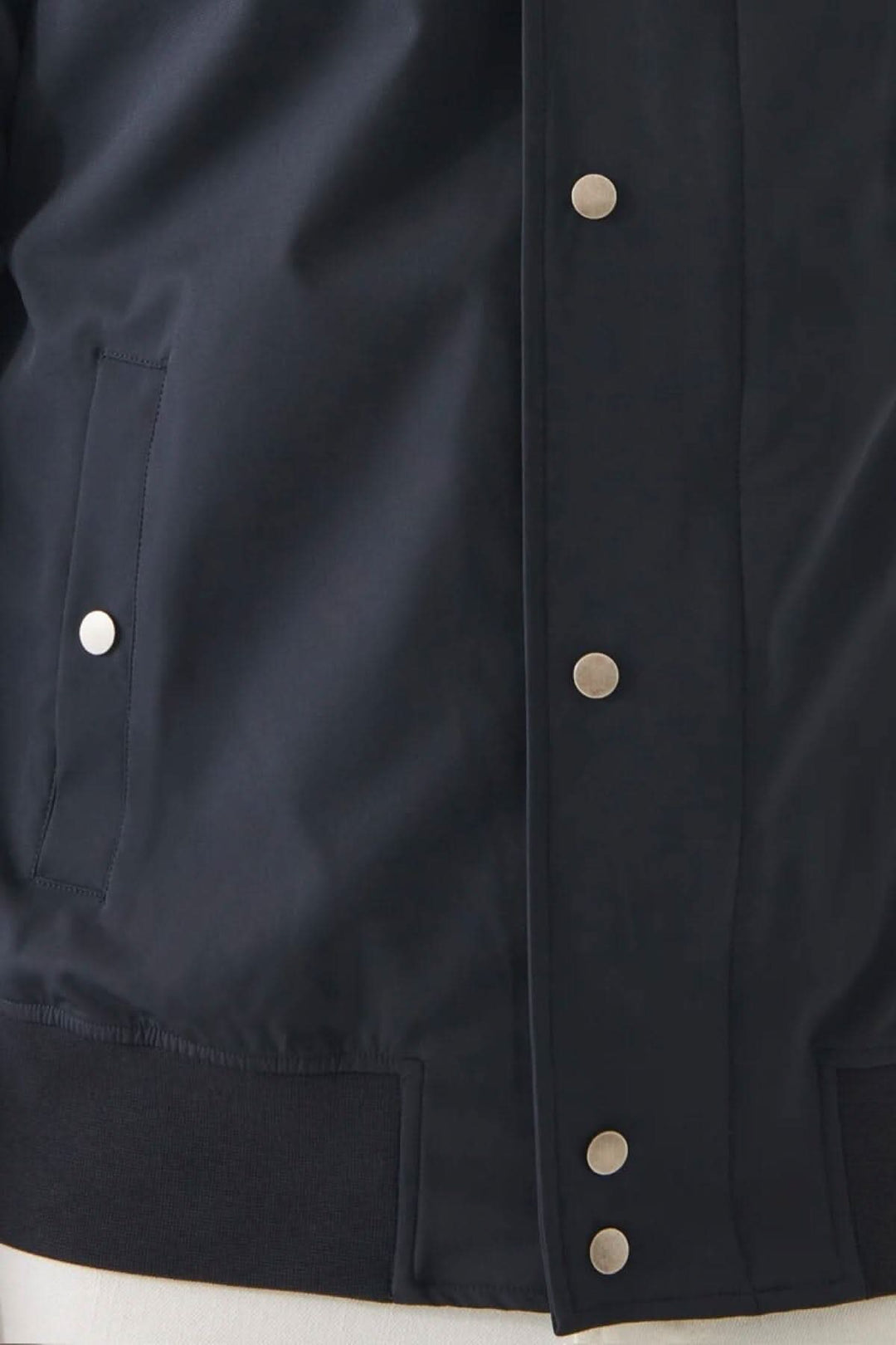 Détail de la veste bomber en nylon extensible avec boutons pression et poches.