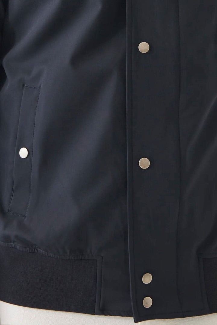Détail de la veste bomber en nylon extensible avec boutons pression et poches.