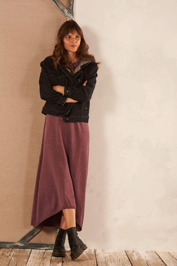 Femme portant une veste en jean avec capuchon, manches longues, et une longue robe mauve.