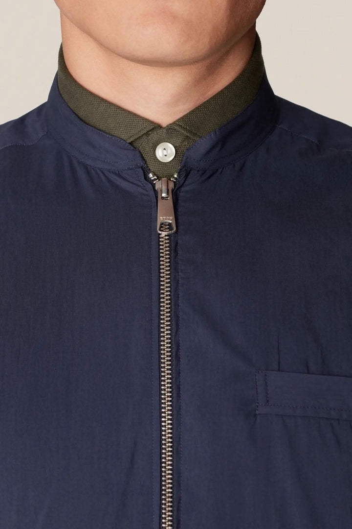 Gilet sans manche bleu avec col vert, idéal pour le style contemporain et la superposition en extérieur.