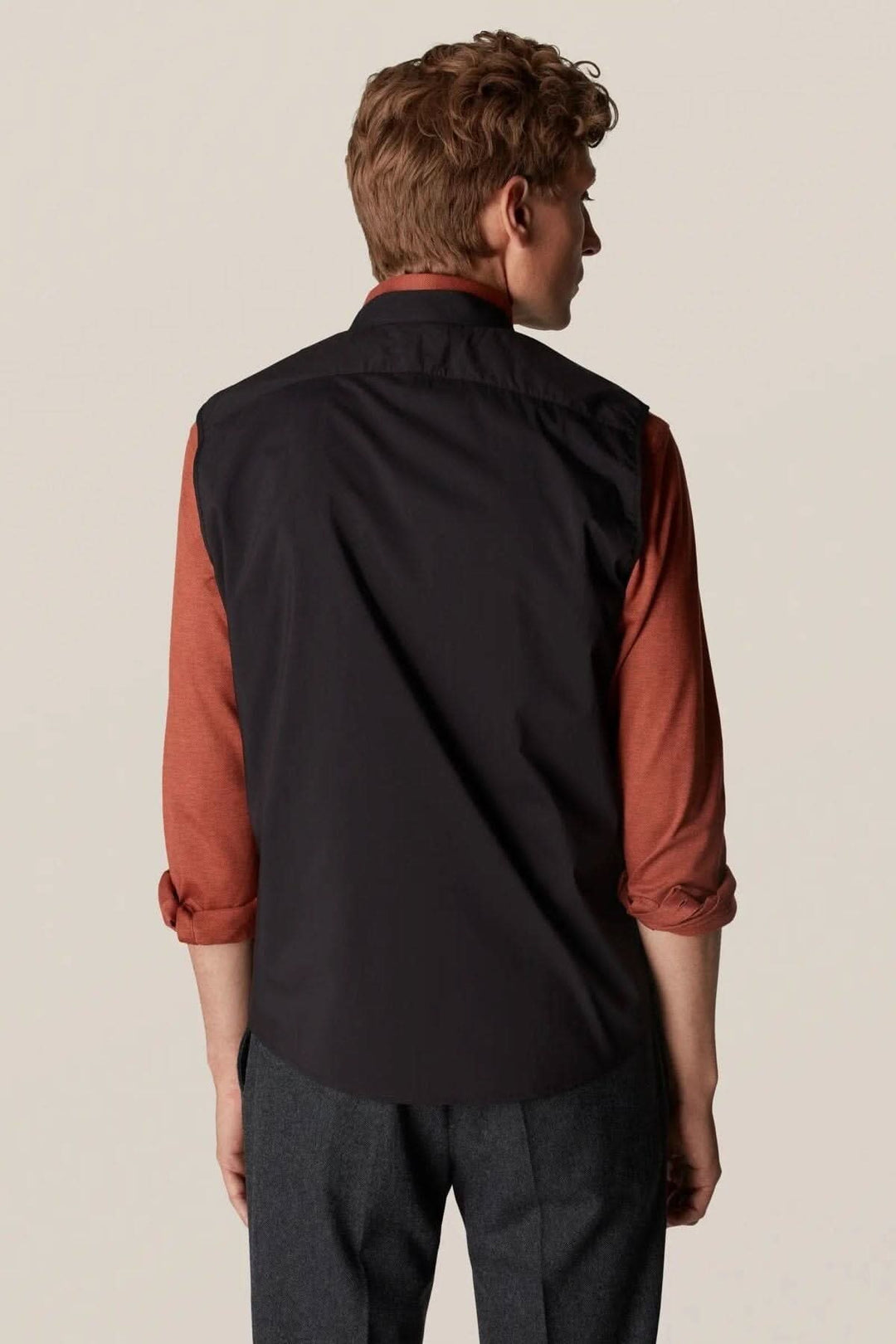 Homme portant une veste sans manches déperlante, vue de dos, style contemporain et élégant pour l'extérieur.