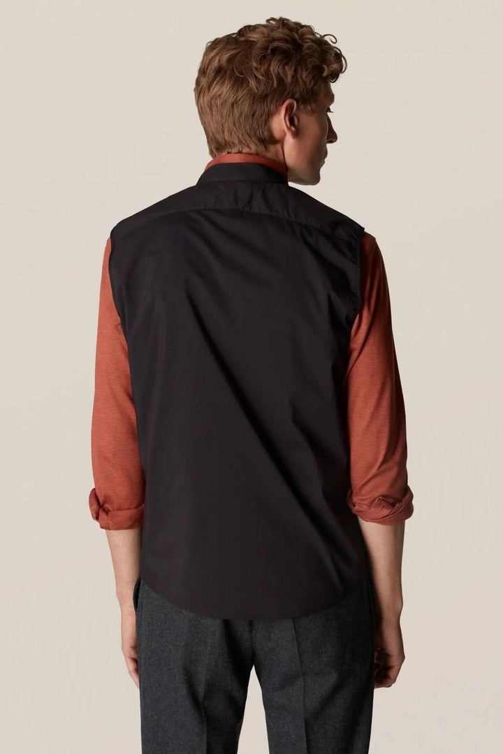 Homme portant une veste sans manches déperlante, vue de dos, style contemporain et élégant pour l'extérieur.