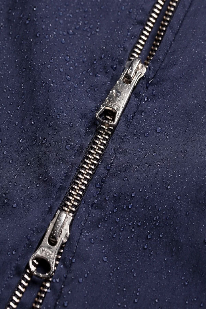 Gros plan sur une fermeture éclair d'une veste déperlante, avec des gouttes d'eau sur le tissu.