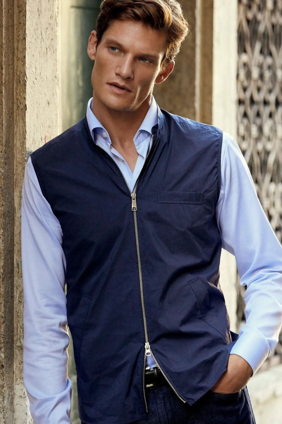 Homme portant une veste sans manches élégante et déperlante, idéale pour l'extérieur, avec une chemise blanche.