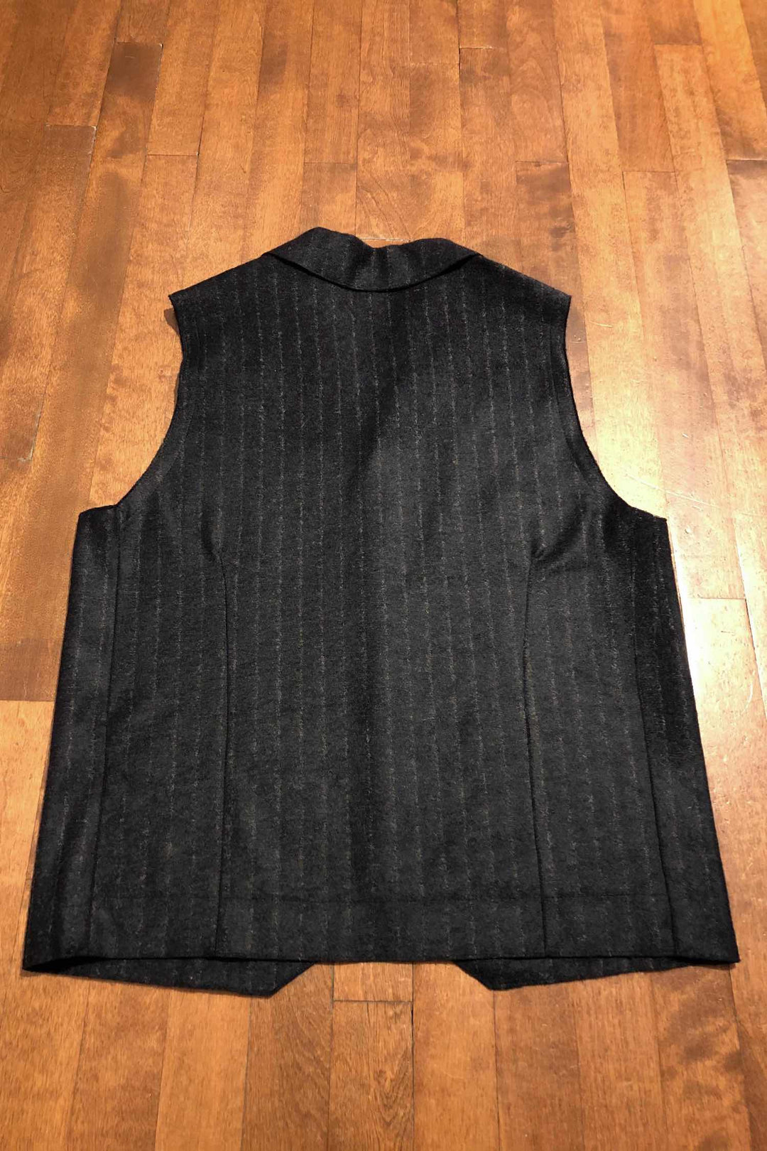 Veste sans manches bleu marine à rayures grises sur fond en bois.